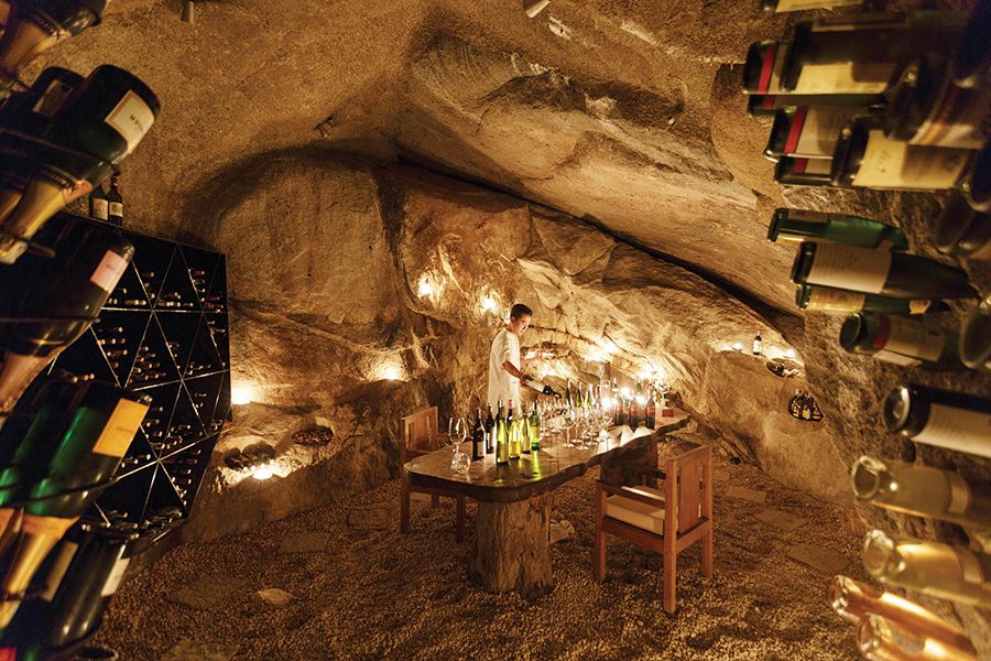 A man pours a bottle of wine in a glass at the Wine Cave restaurant at Six Senses Ninh Van Bay, a unique dining experience  