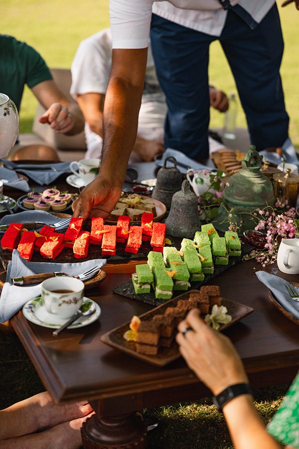 A man serving delicate snacks and tea on a table outdoors 