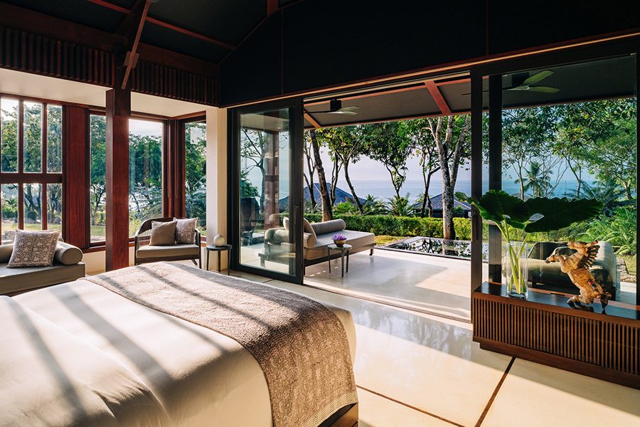 A guest suite at Ani Sri Lanka resort opens onto a leafy terrace with natural scenery in the background