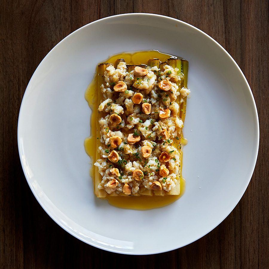 A dish with hazelnuts on vegetables in a clear brown sauce at Cafe Paci, Sydney. 