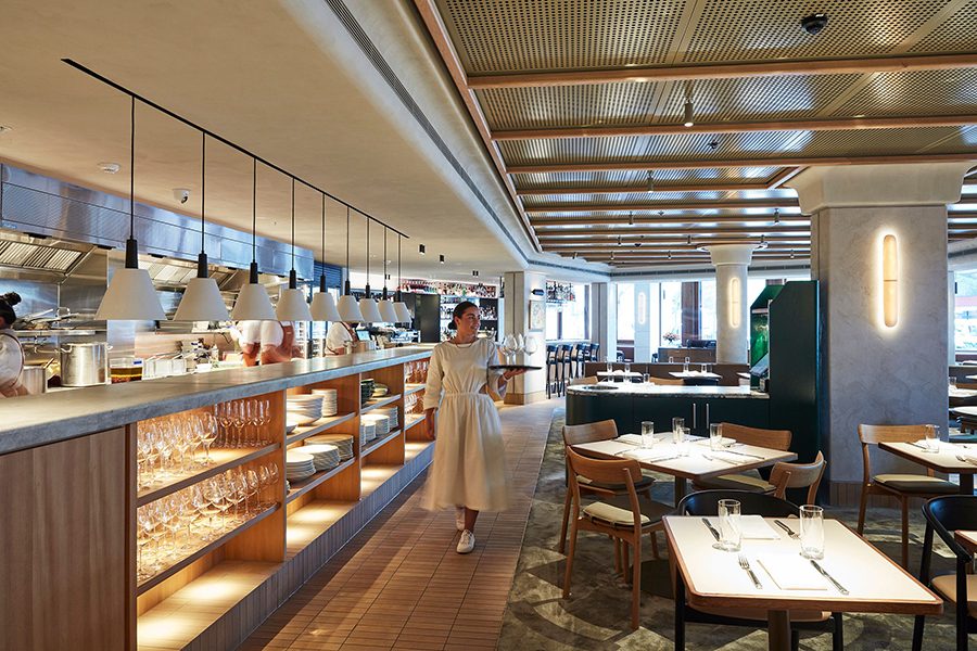 A woman walks towards the camera past tables and the open kitchen of Margaret in Sydney