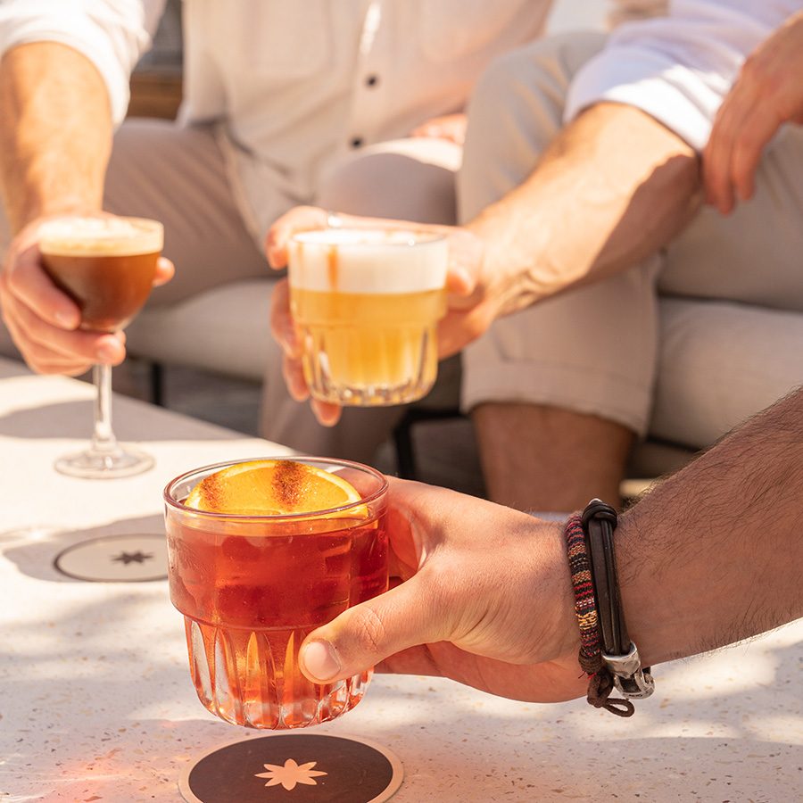 Closeup of hands holding three cocktails