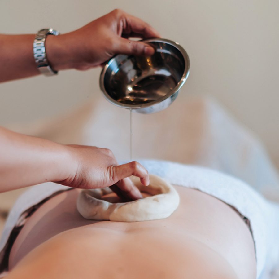A massage therapist pours a clear liquid onto a woman’s back at Escape Haven.