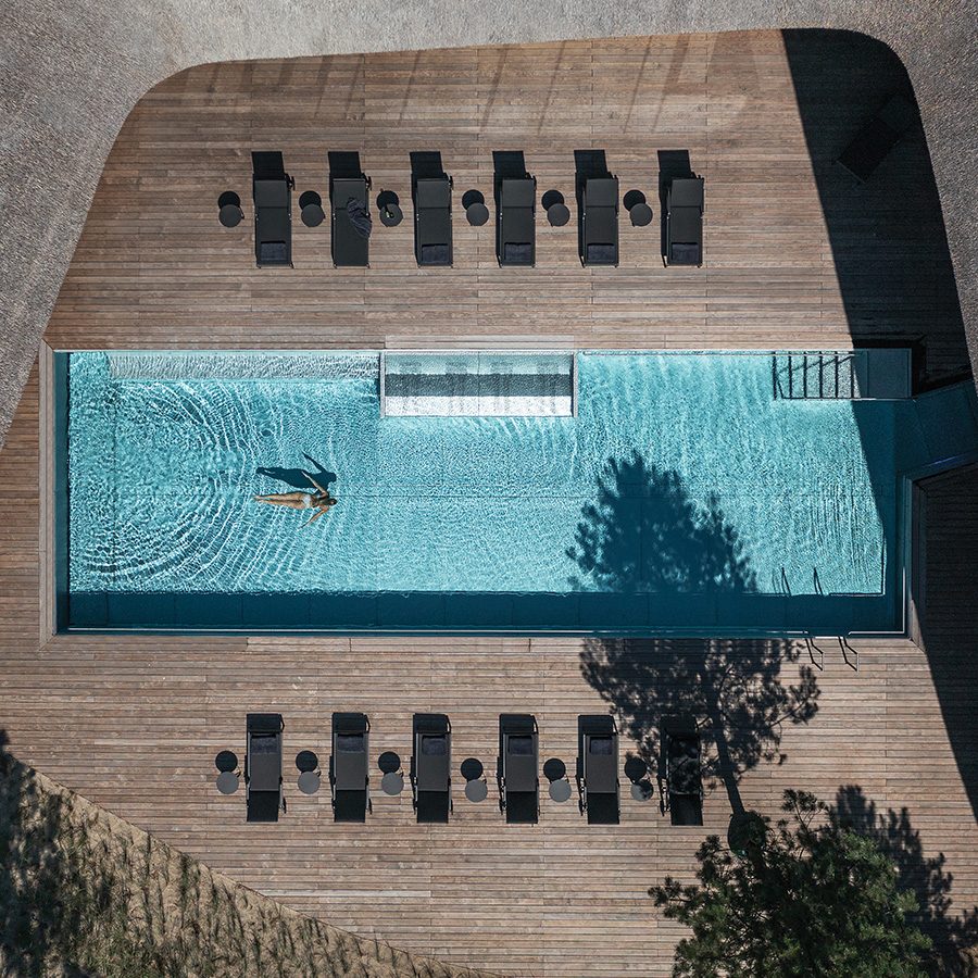 Aerial view of the rectangular swimming pool at Lanserhof Sylt. A lone woman in a bikini swims in the pool.