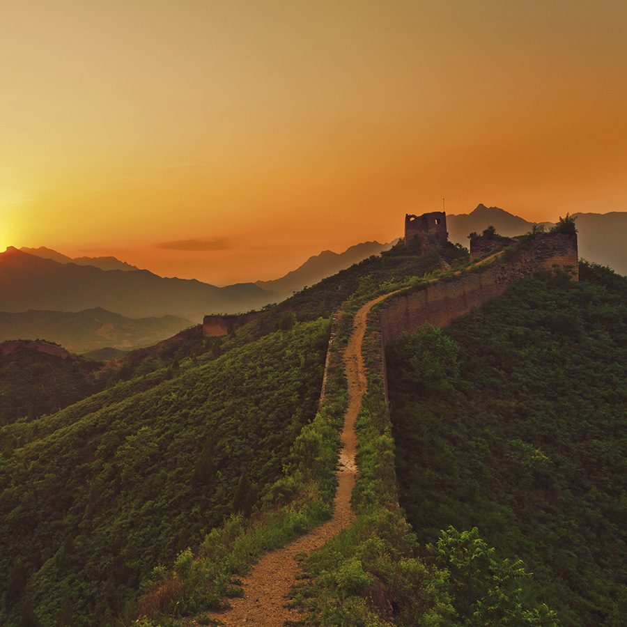 A segment of the Great Wall lit up by an orange sun.