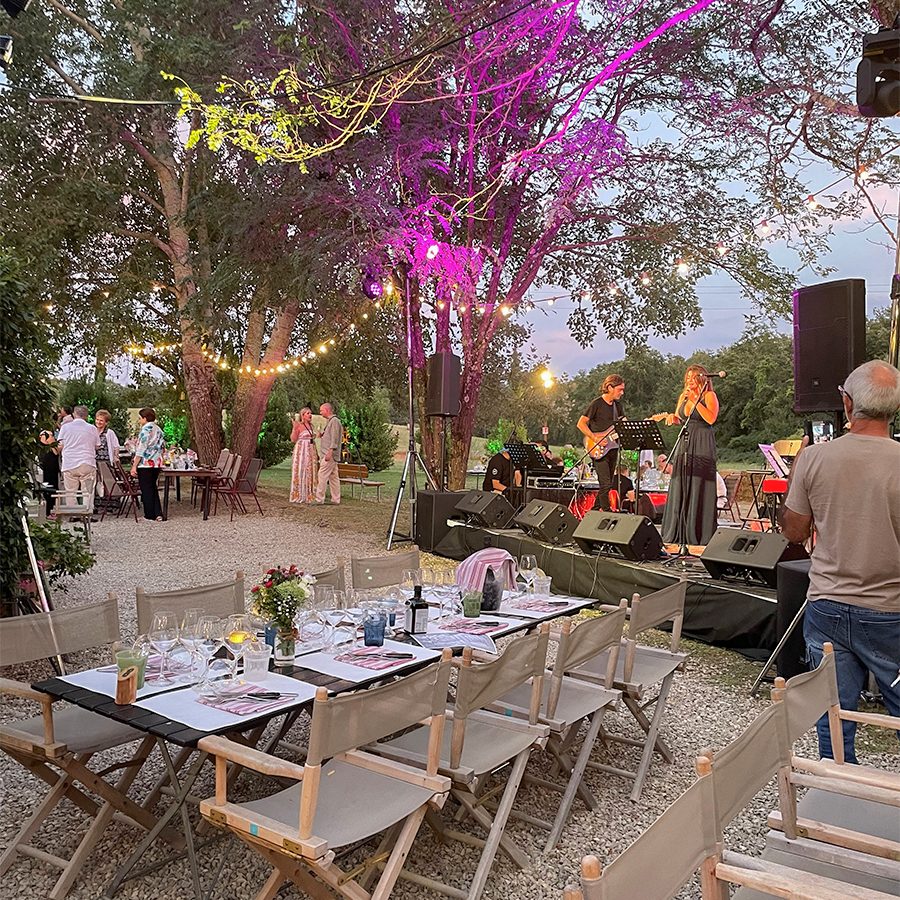 Grey folding chairs and a table set for dinner. The band can be seen in the background. 