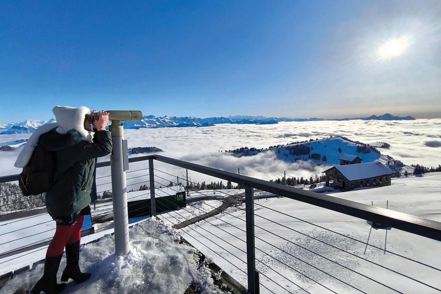 Cathay Pacific Flight Purser Julie Heng looking through a tower viewer at the snowy surroundings atop Mount Rigi in Switzerland. 