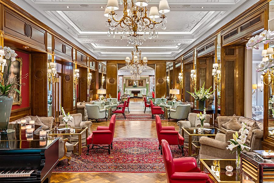 An opulent lobby lined with lounge-style tables and chairs, and fitted with chandeliers, at Hotel Europäischer Hof Heidelberg 