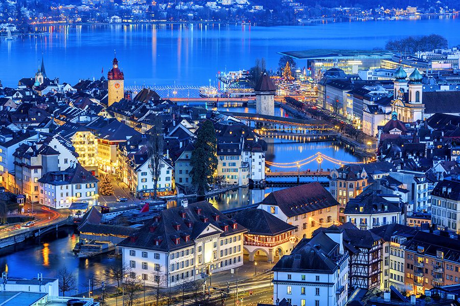 A view of traditional buildings in Lucerne, with Lake Lucerne in the background, at twilight 