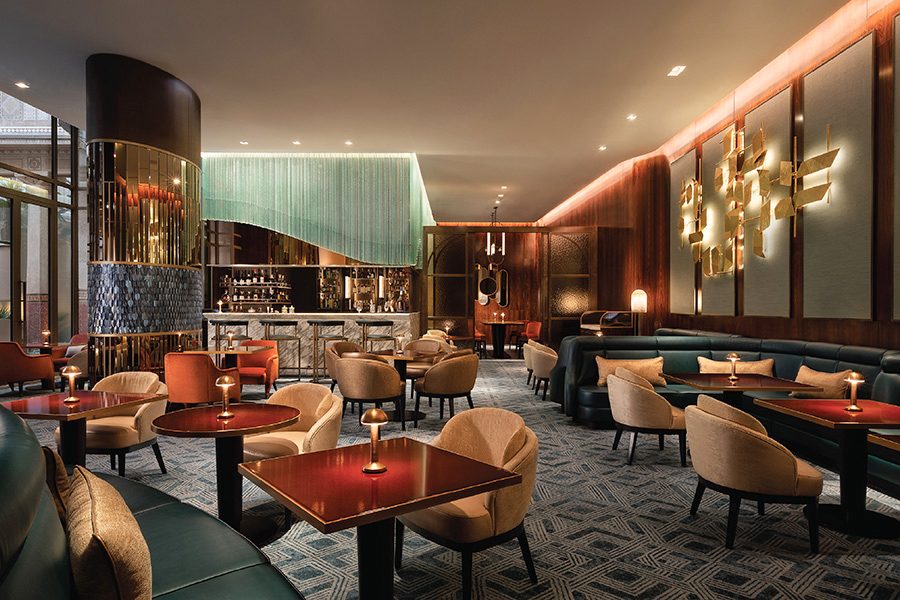 A softly lit lounge filled with tables and chairs at Prince de Galles, a Luxury Collection Hotel 
