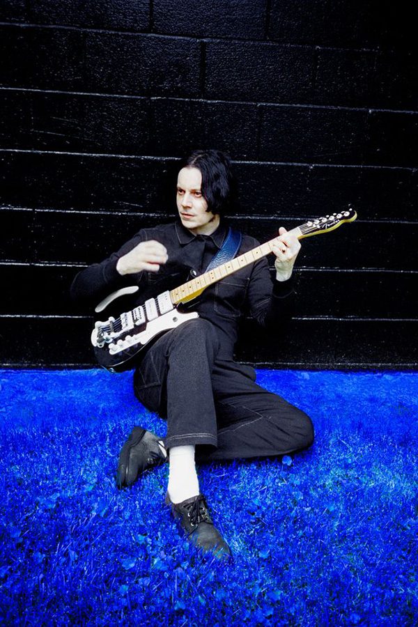 Jack White playing guitar on a blue floor,