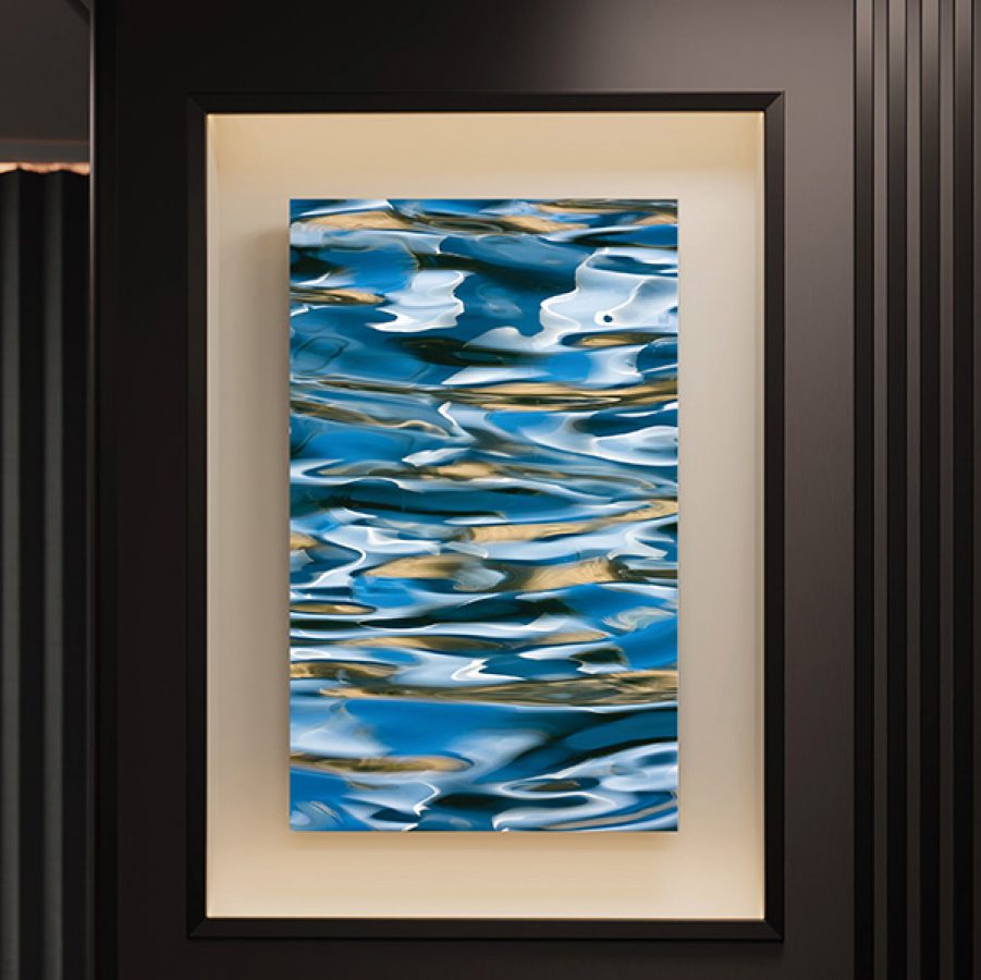 A photo of blue and gold ripples on the surface of Hudson River in a black frame.