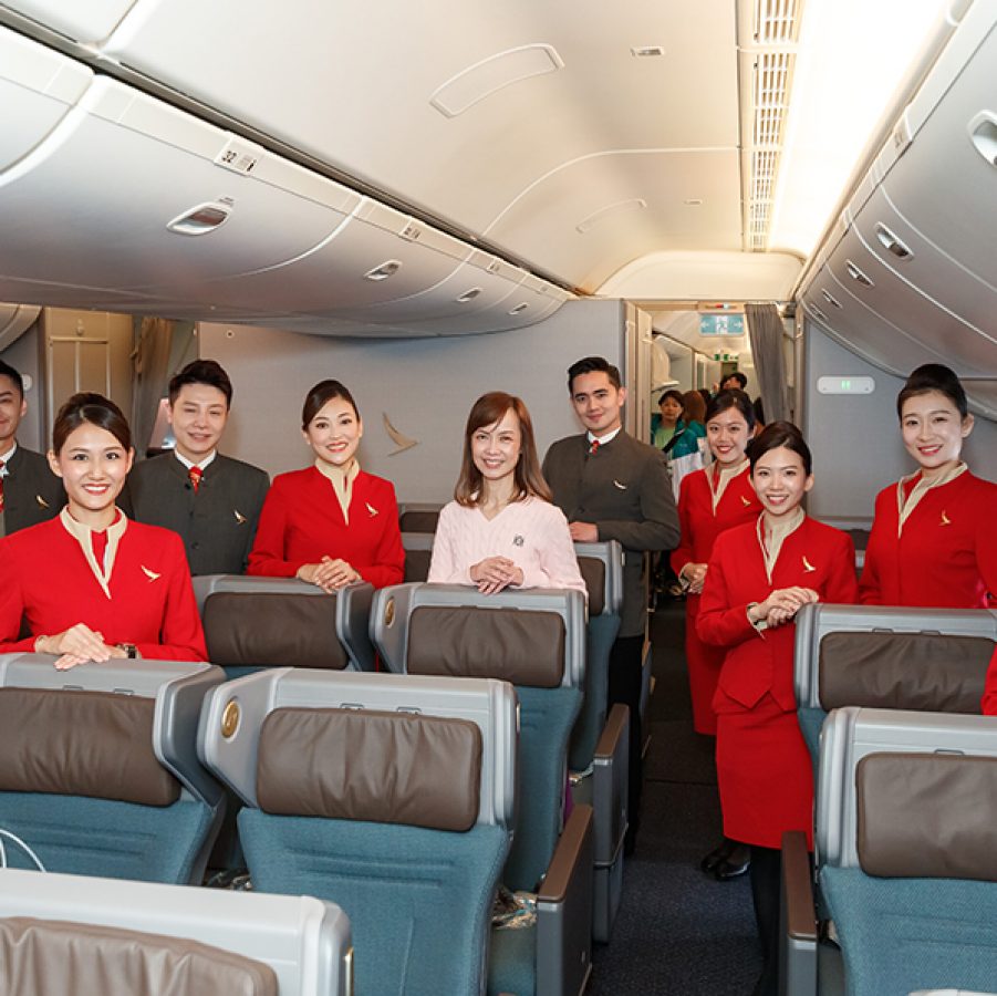 Cathay Pacific cabin crew and team member pose for a photo inside an airplane 