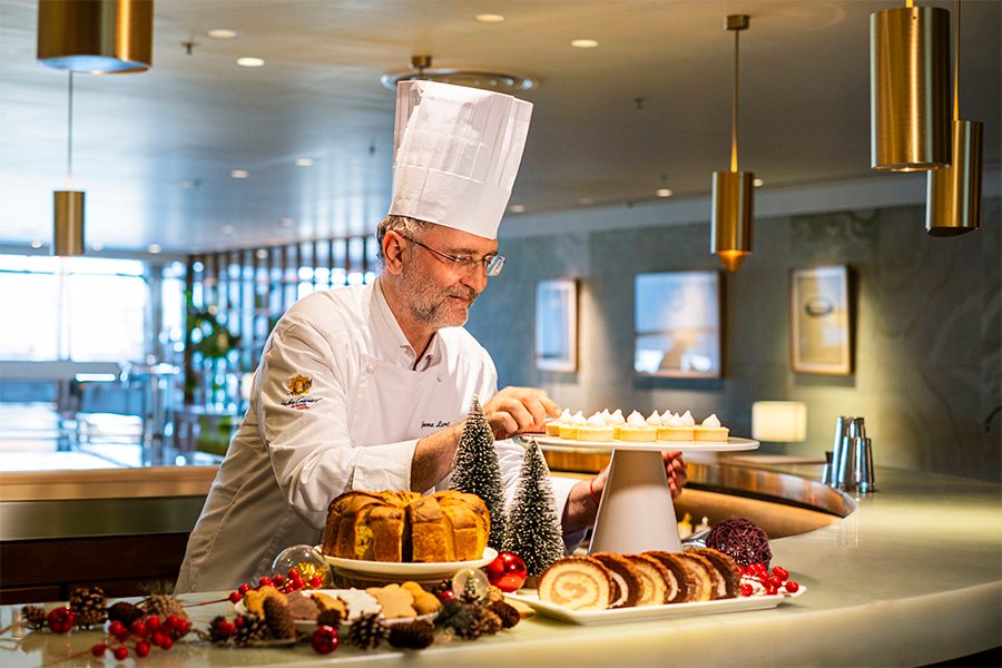 Chef Jerome standing over plates of Christmas dessert at the Cathay lounge. 