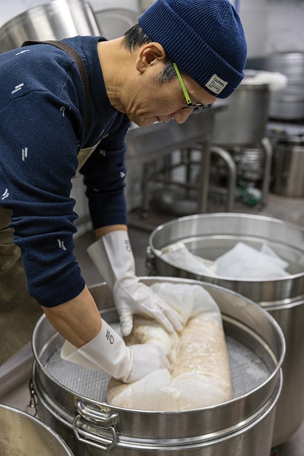 A man straining makgeolli from fermented rice.