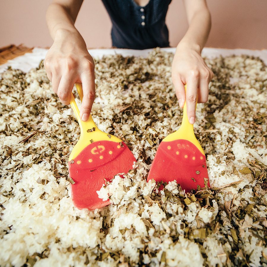 A person using spatulas to prepare the rice used to make makgeolli.
