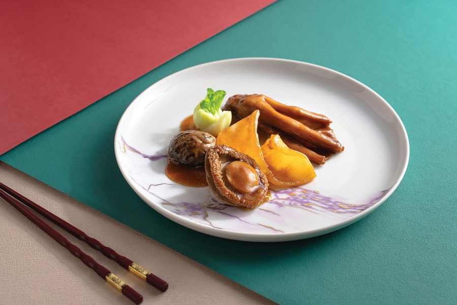 A white marbled plate with braised abalone and mushroom at The Jade, Regala Skycity Hotel, Hong Kong. A pair of chopsticks are next to the plate.