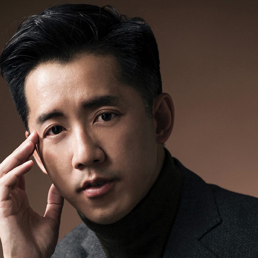 Hotel designer André Fu looking at the camera in front of a brown background