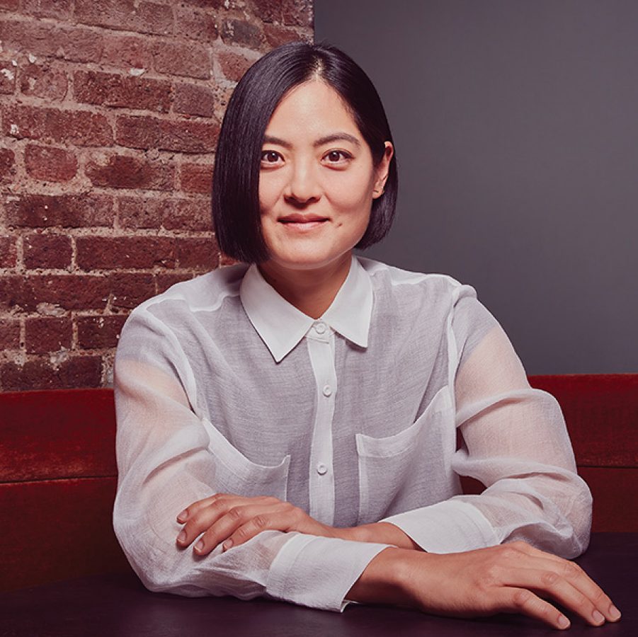 Hotel designer Joyce Wang looking at the camera, seated on a red couch