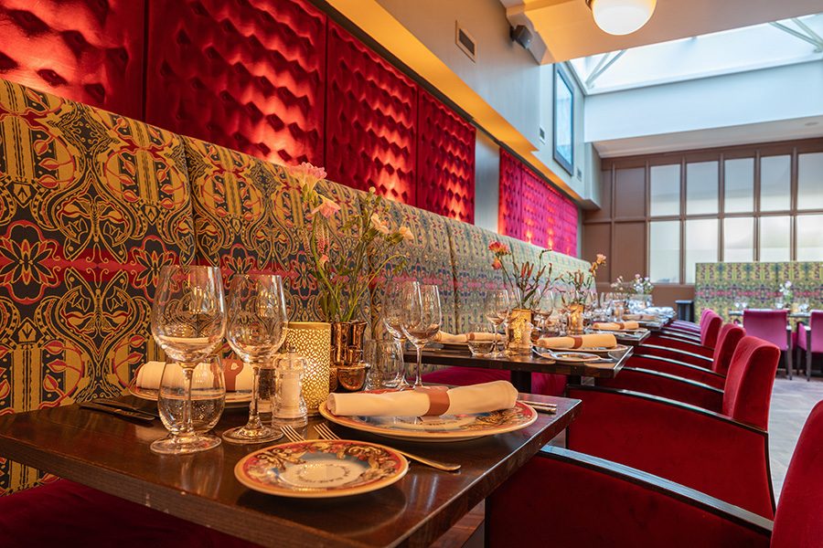 A set of dining tables and chairs at a restaurant in Grand Hotel Amrâth Amsterdam with plates and wine glasses on the tables.