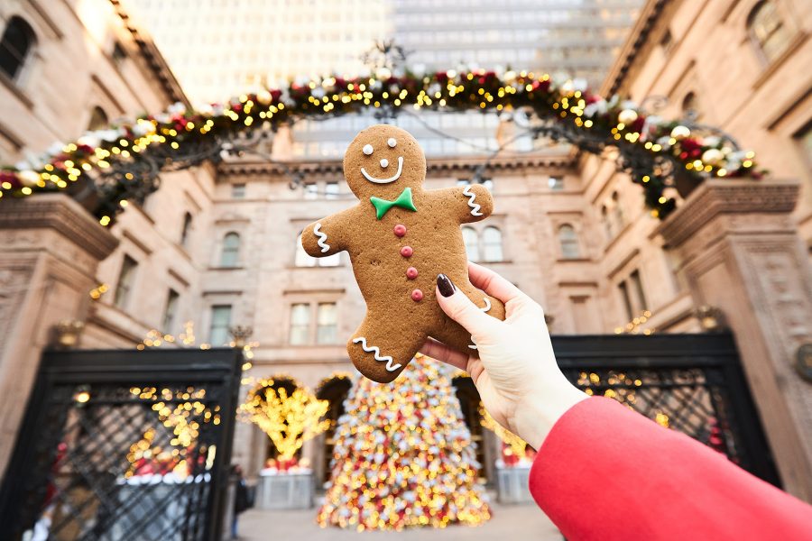 A woman's hand holding up a gingerbread man cookie in front of Lotte New York Palace
