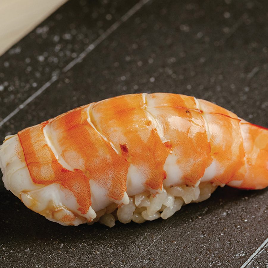 Close-up of double shrimp sushi on a black slate plate.