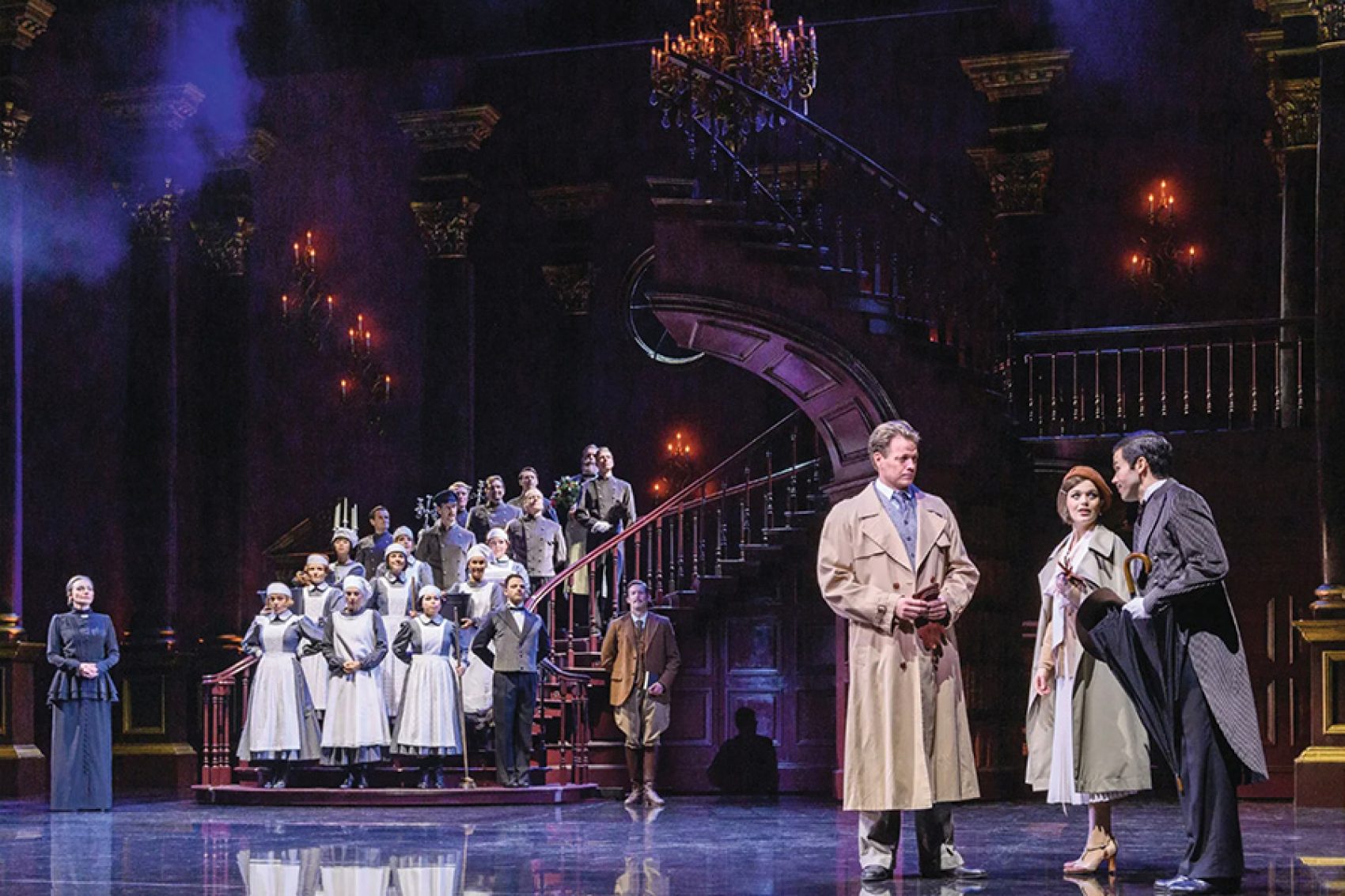 Actors on a stage with a winding staircase, gilded pillars and a chandelier for German-language staged concert Rebecca.