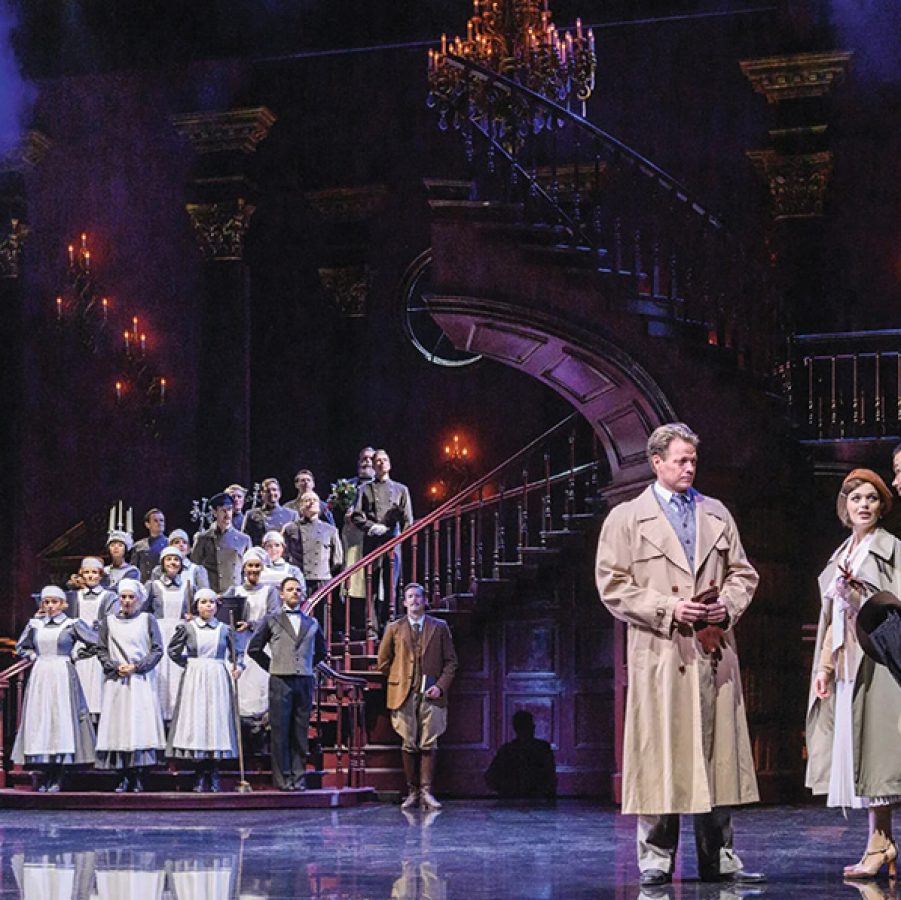 Actors on a stage with a winding staircase, gilded pillars and a chandelier for German-language staged concert Rebecca.