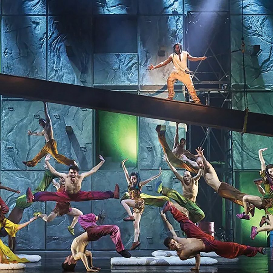 A group of people in colourful clothes dancing on stage for Notre-Dame de Paris.  