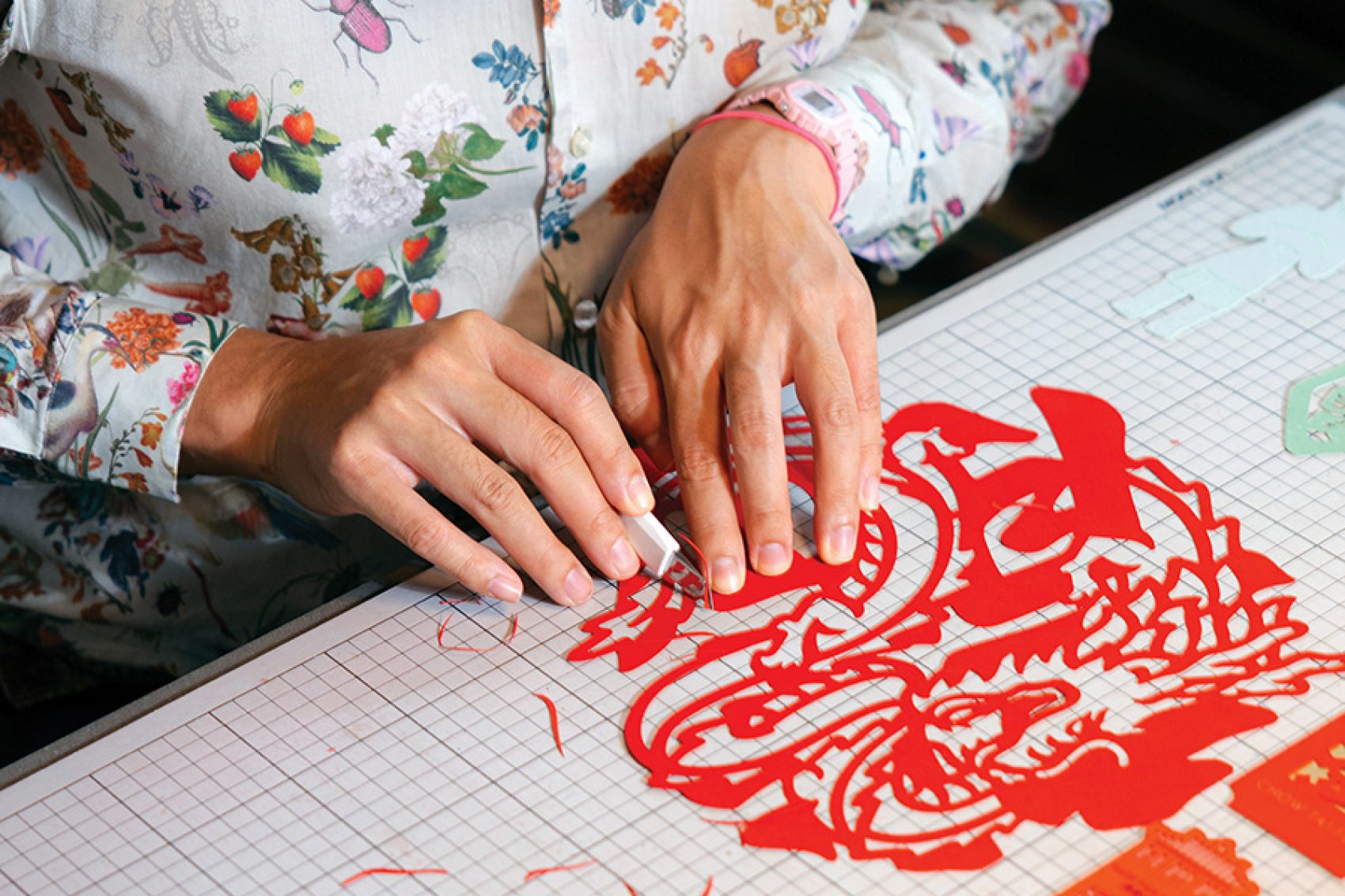 Nick Tsao cutting a Chinese-inspired design from red paper.