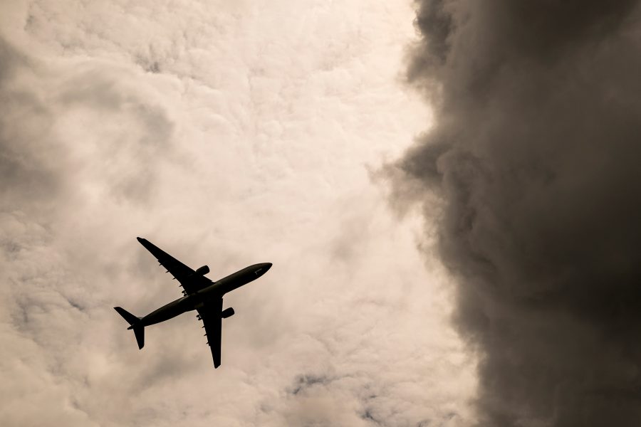 A plane flying in the sky amidst stormy clouds.