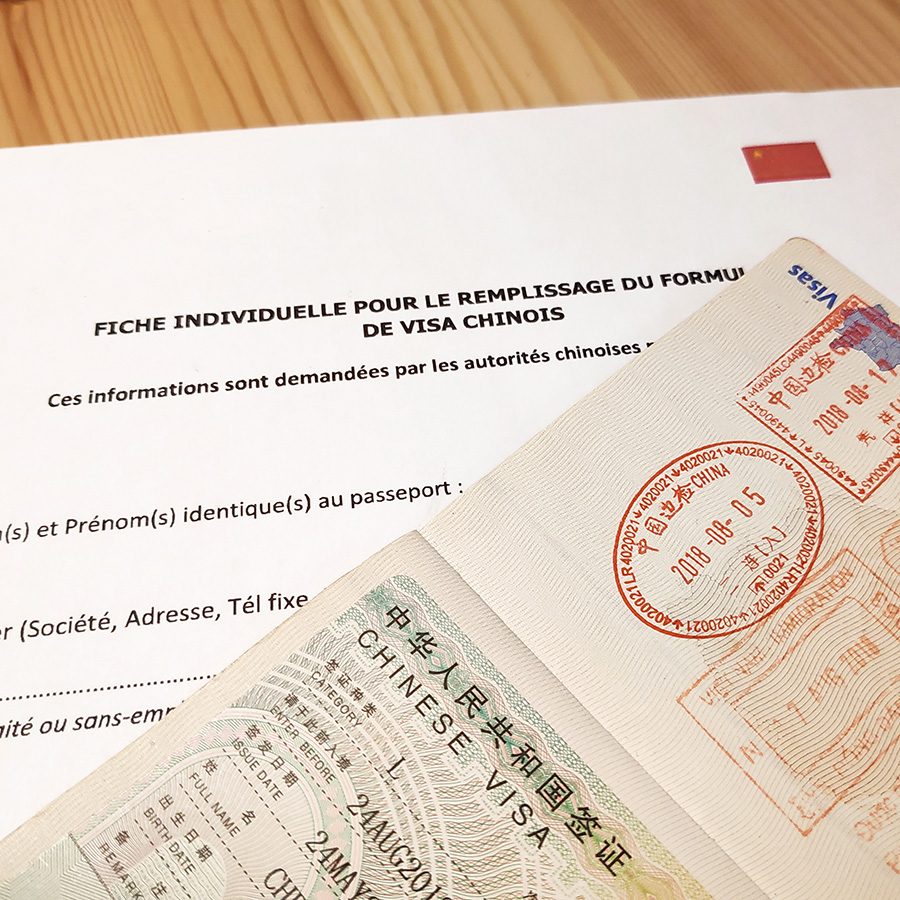 Documents to complete for a Chinese visa application, spread out on a table. 