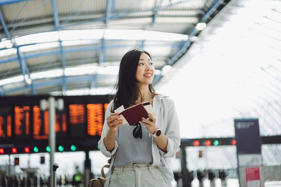 A young woman looks at her travel documents inside a train station