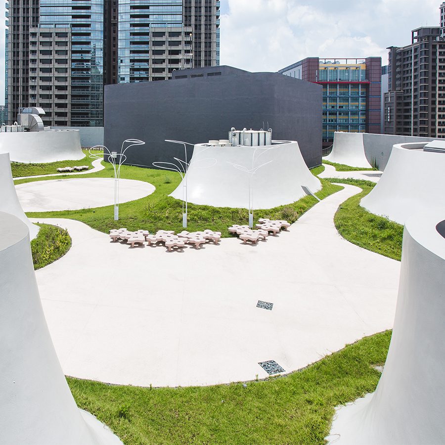 An open space with curved structures and greenery at National Taichung Theatre. 