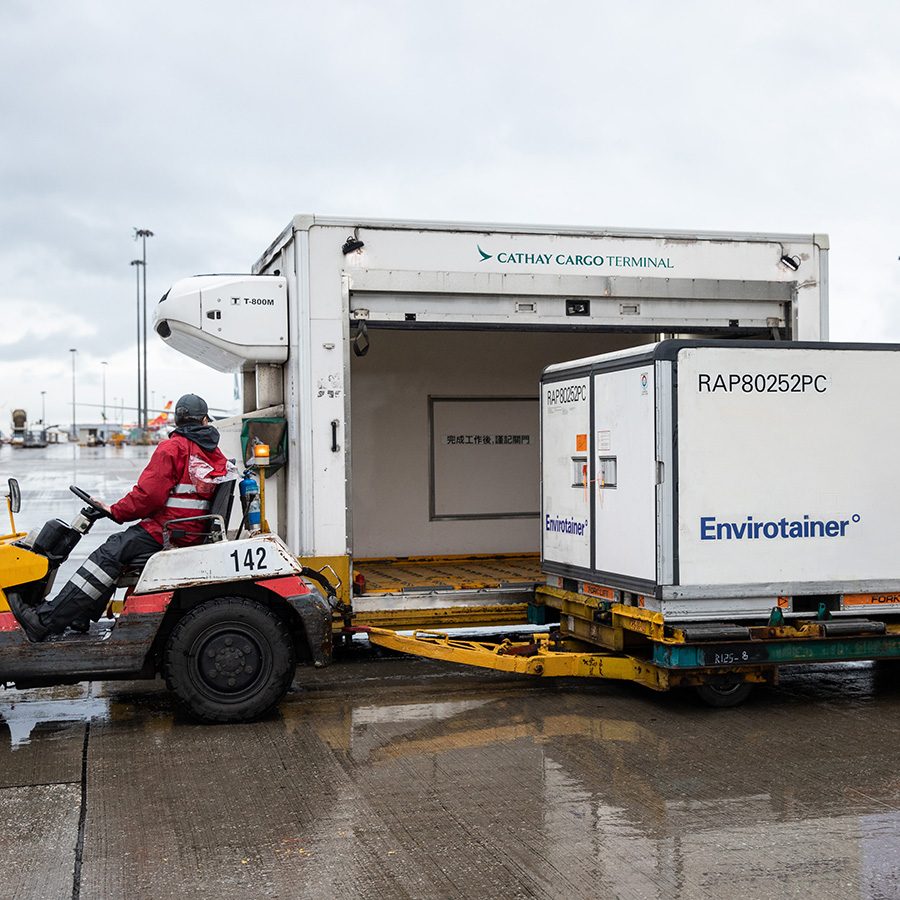 A Cathay Cargo unit being transported. A man sits at the wheel of the vehicle. 