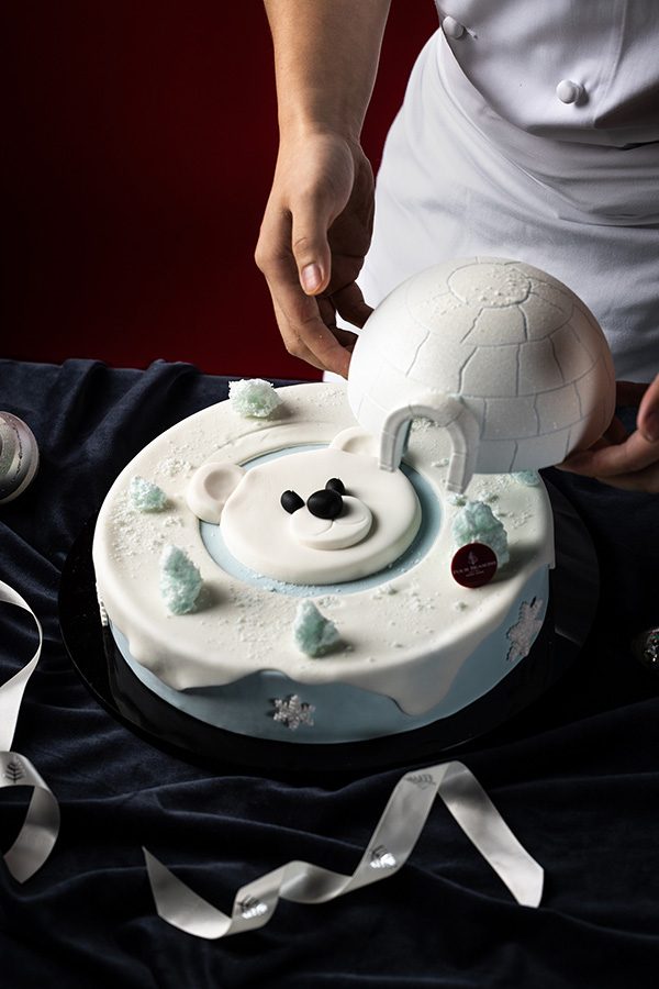 An igloo- and polar bear-themed cake placed on a table, available on the Four Seasons online shop for the holidays. 