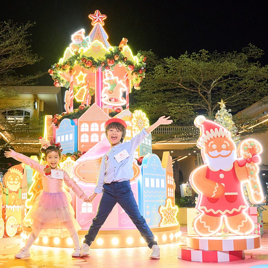  Two children posing for a picture in front of Gold Coast Christmas Market’s cheery holiday light installations.