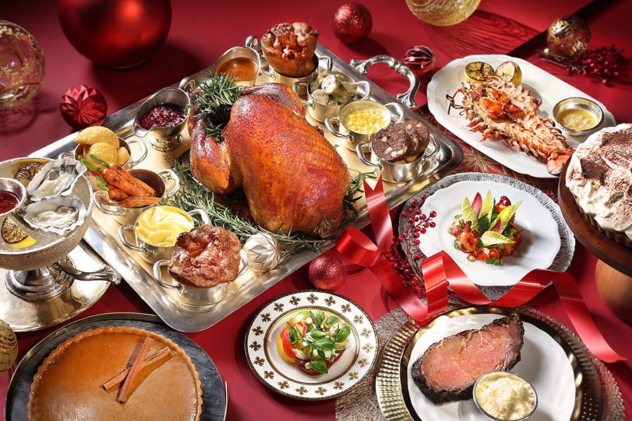  A spread of Christmas feast staples on a red table, from roast turkey and its trimmings to pie and lobster.  
