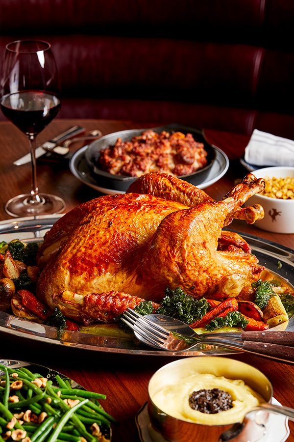 A close up of a thanksgiving meal, whole roasted turkey with vegetables, pudding and red wine on a dining table served at Henry in Rosewood Hong Kong