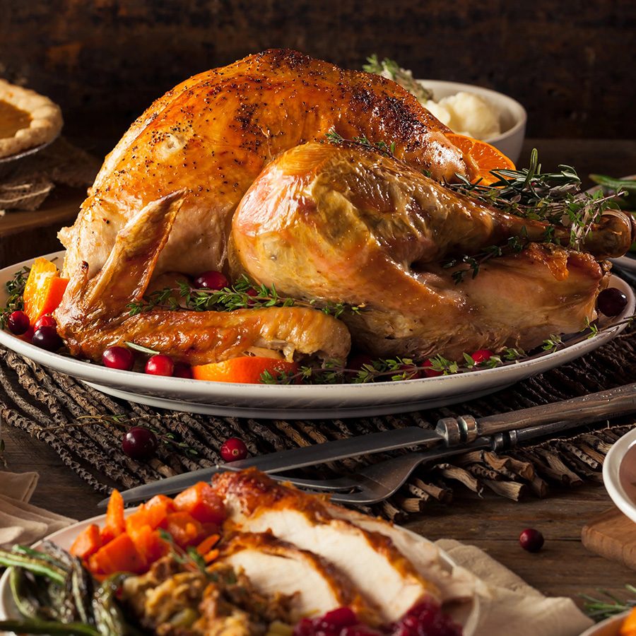 A closeup of a Thanksgiving meal with whole roasted turkey, gravy, classic side dishes, vegetables, pecan pie and pumpkins on a dining table served at Quiero Más, Central Hong Kong.
