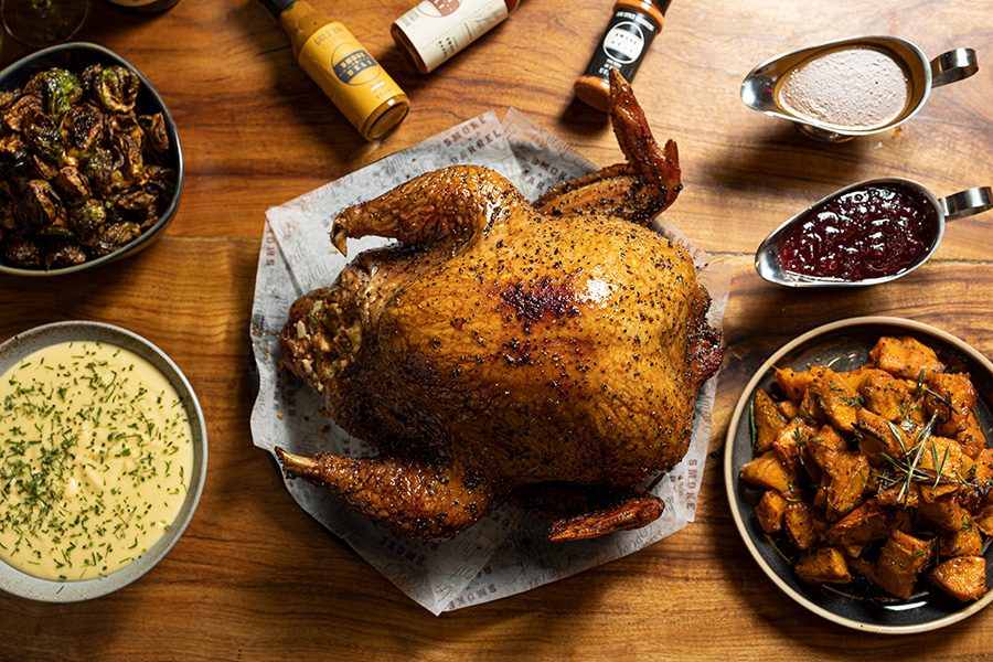 A top down view of a Thanksgiving meal, whole roasted turkey, vegetables and sauces from Smoke & Barrel.