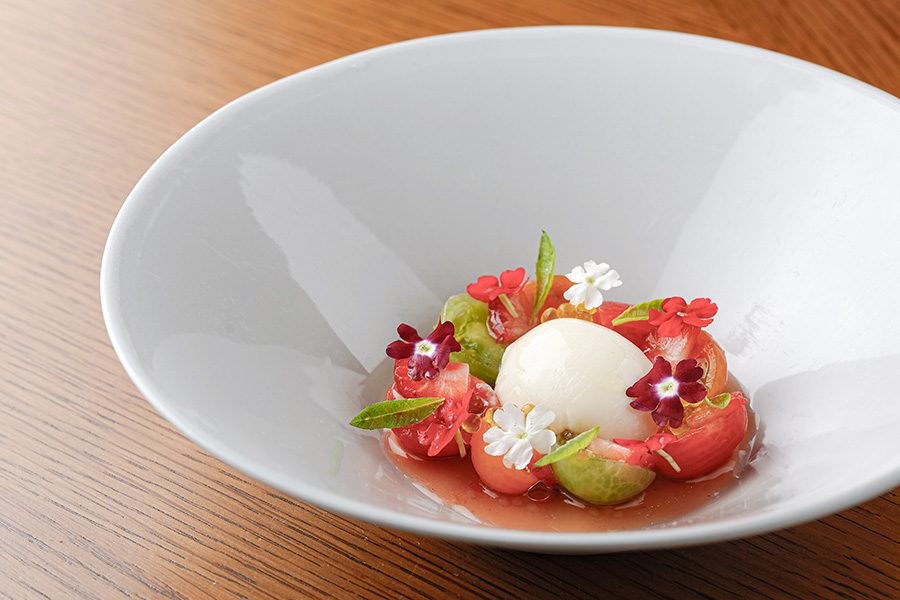 A white dish with heirloom tomato and soymilk burrata served at Amber, Hong Kong. 