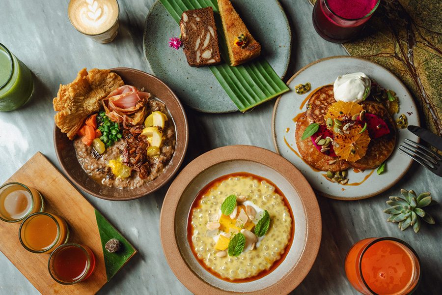 A spread with cakes, pancakes, rice and glasses of juice at Tanaman, Desa Potato Head, Bali. 