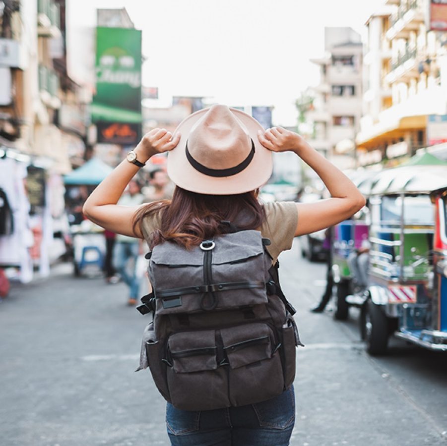 Woman wearing hat and backpack in the middle of a street 