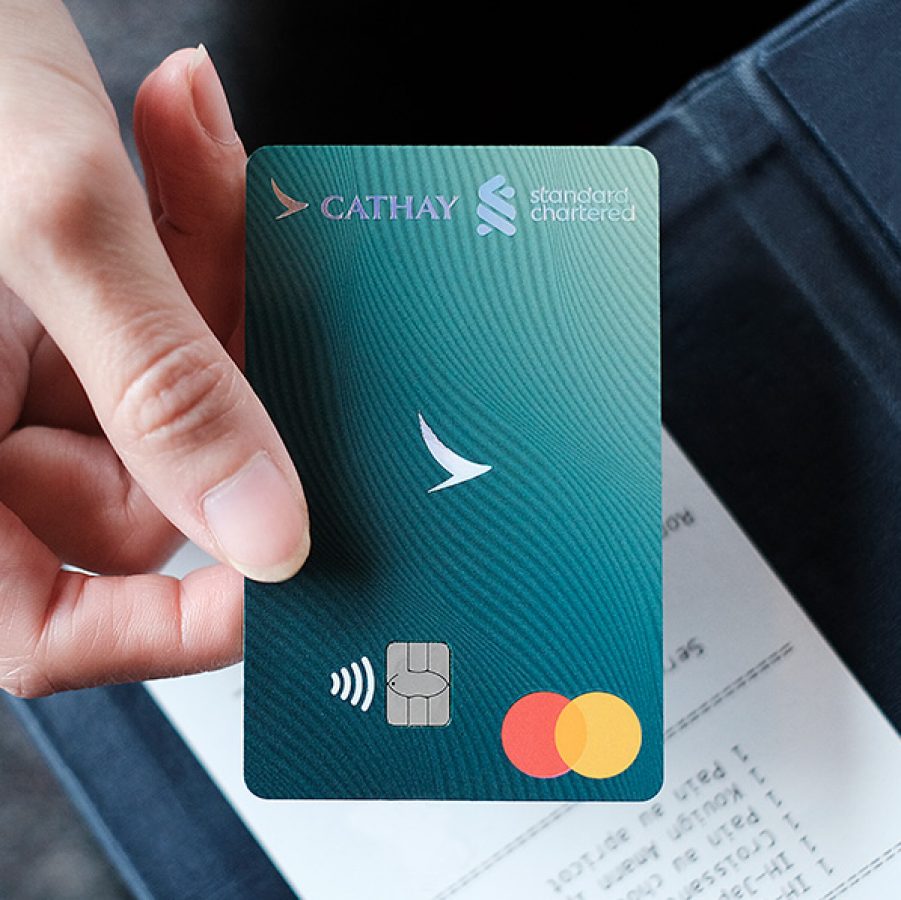 Person holding a Standard Chartered Cathay Mastercard over a bill