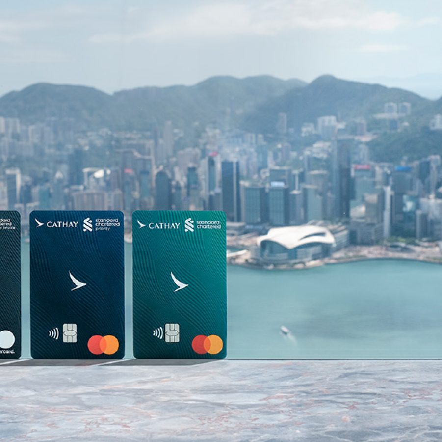 Three different versions of the Standard Chartered Cathay Mastercard against the Hong Kong skyline