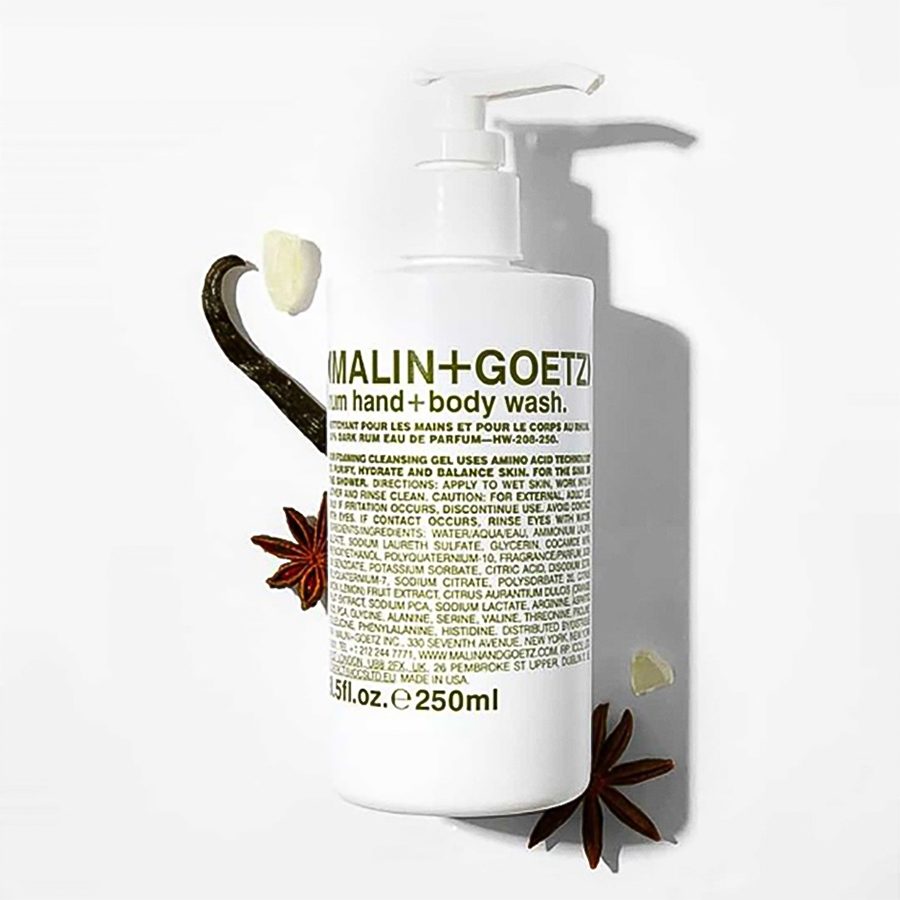 A bottle of Malin+Goetz rum hand + body wash with natural botanical ingredients in the backdrop 