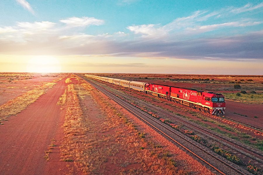 The Ghan train travelling through the Australian landscape at sunrise.