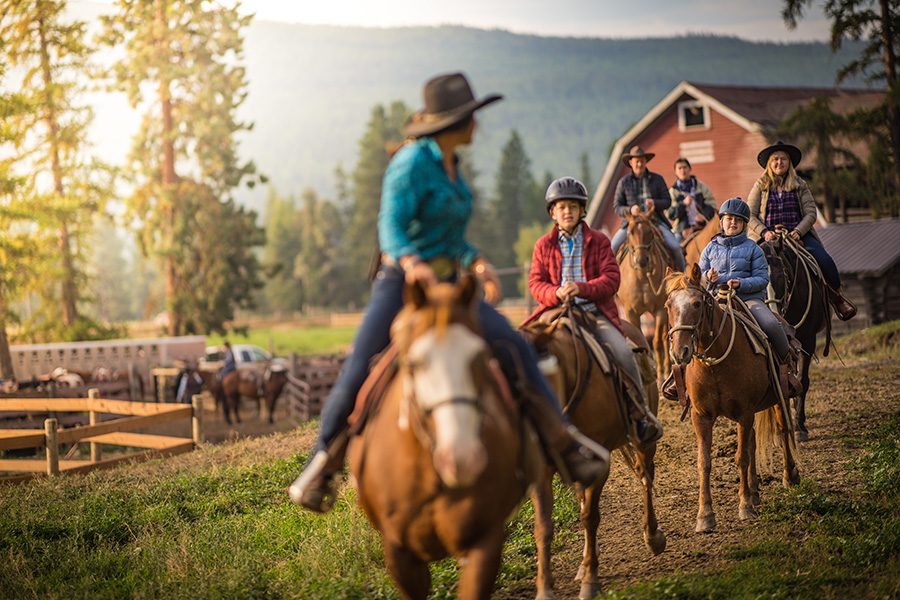 A group of children and adults riding horses at sunrise at Three Bars Guest Ranch. 