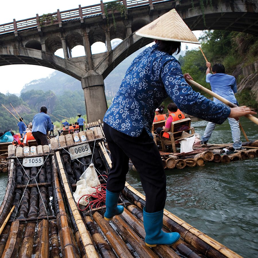 A woman pushes a tourist boat along the Jiuqu River at Mount Wuyi provincial park, Fujian. 